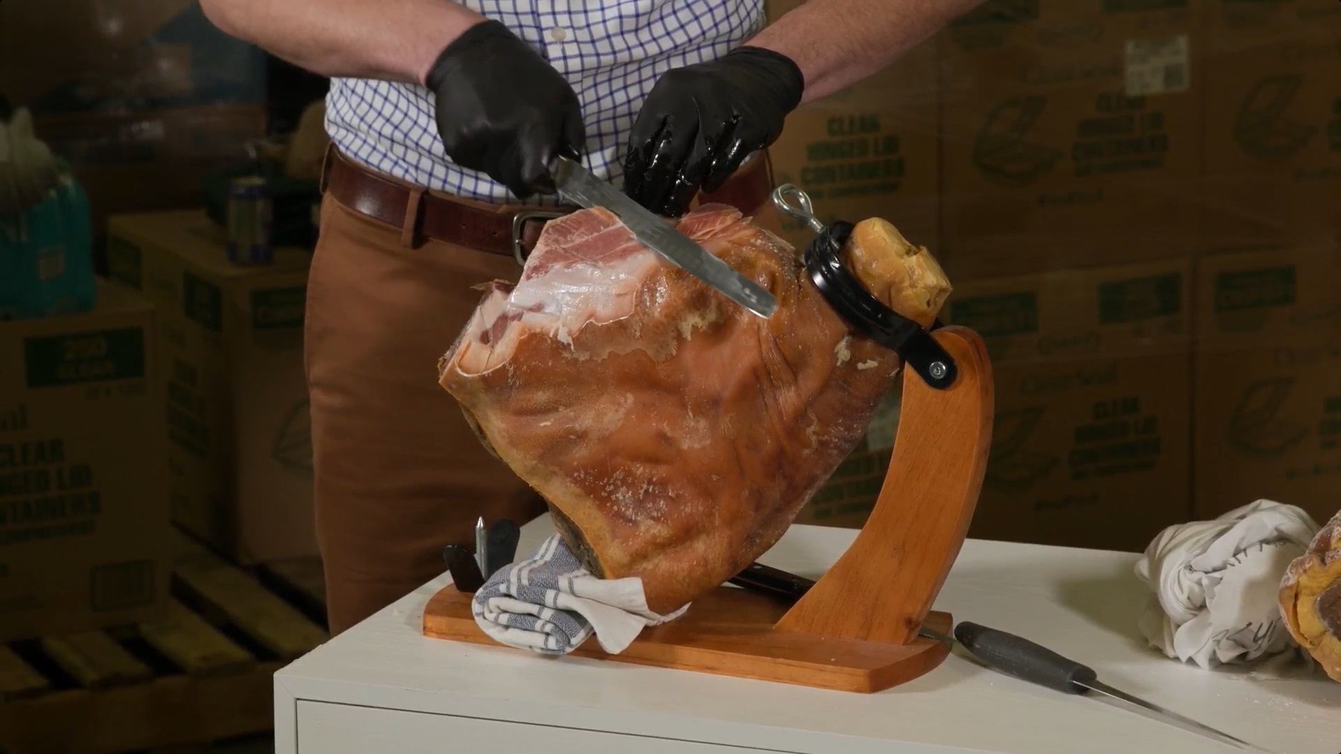 A person standing an cutting into a country ham.