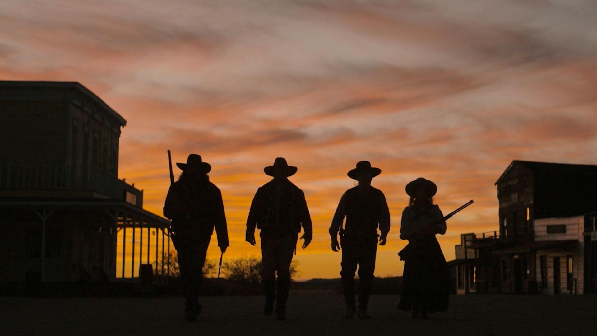 Cowboys silhouetted against a sunset
