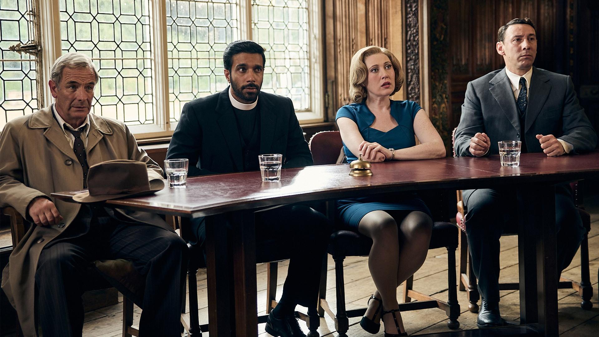 Geordie, Alphy, a woman, and Leonard sit behind a table