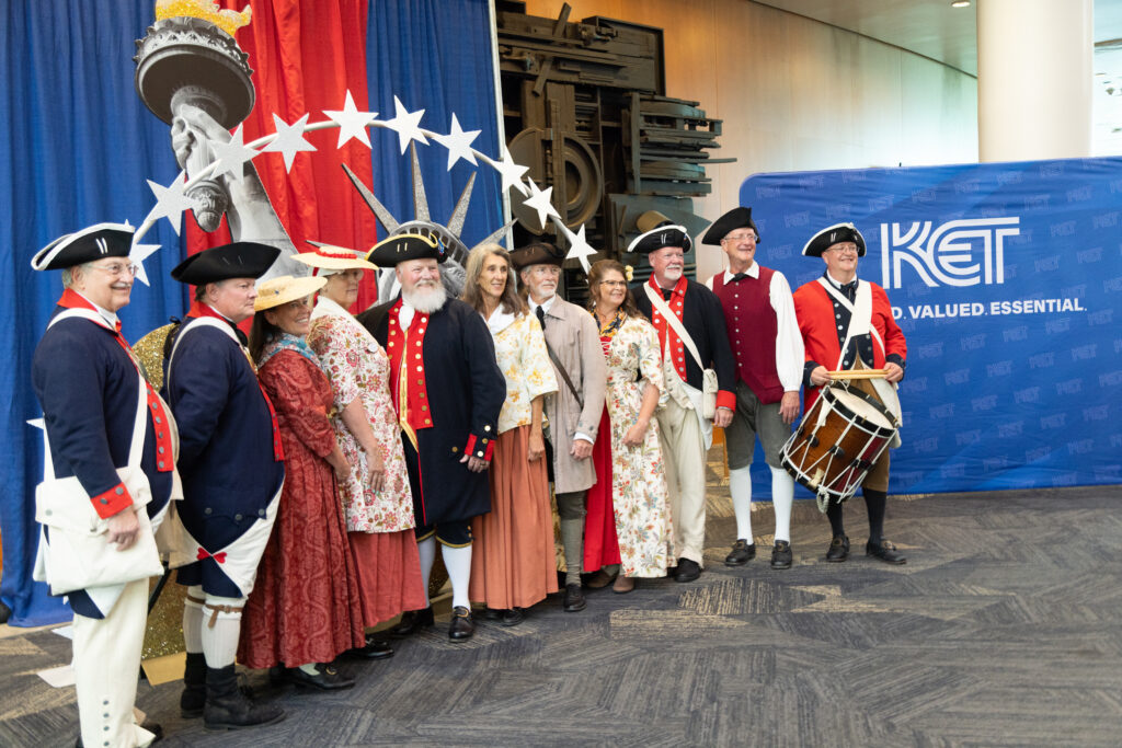 Members of the National Society of the Sons of the American Revolution Color Guard posing with themed decor at KET's Louisville event.