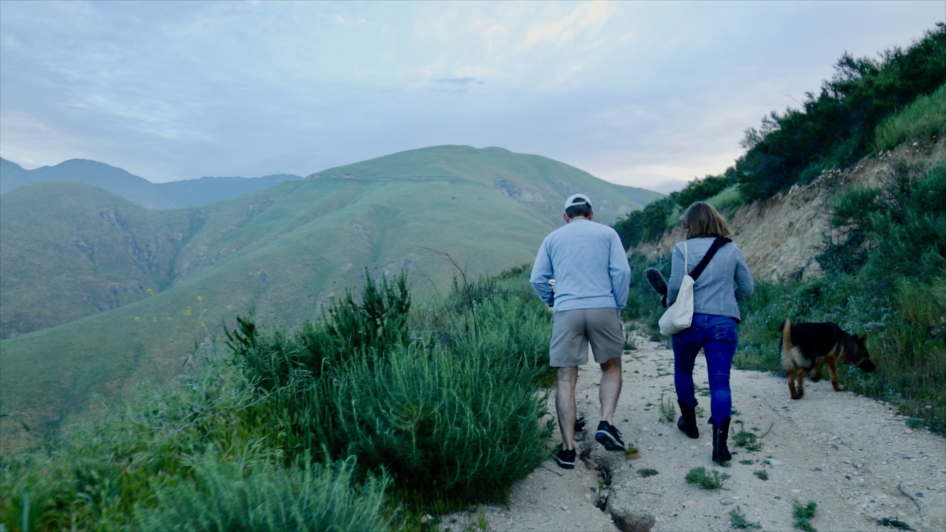 Marvin and Katy photographed from behind as they walk side by side on a mountain trail