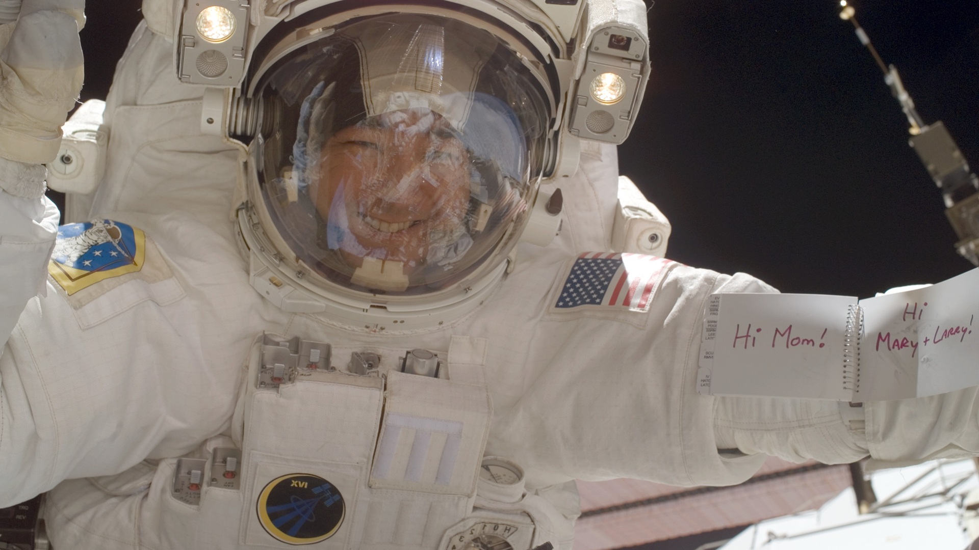 Daniel Tani on a space walk, holding a note that reads Hi Mom