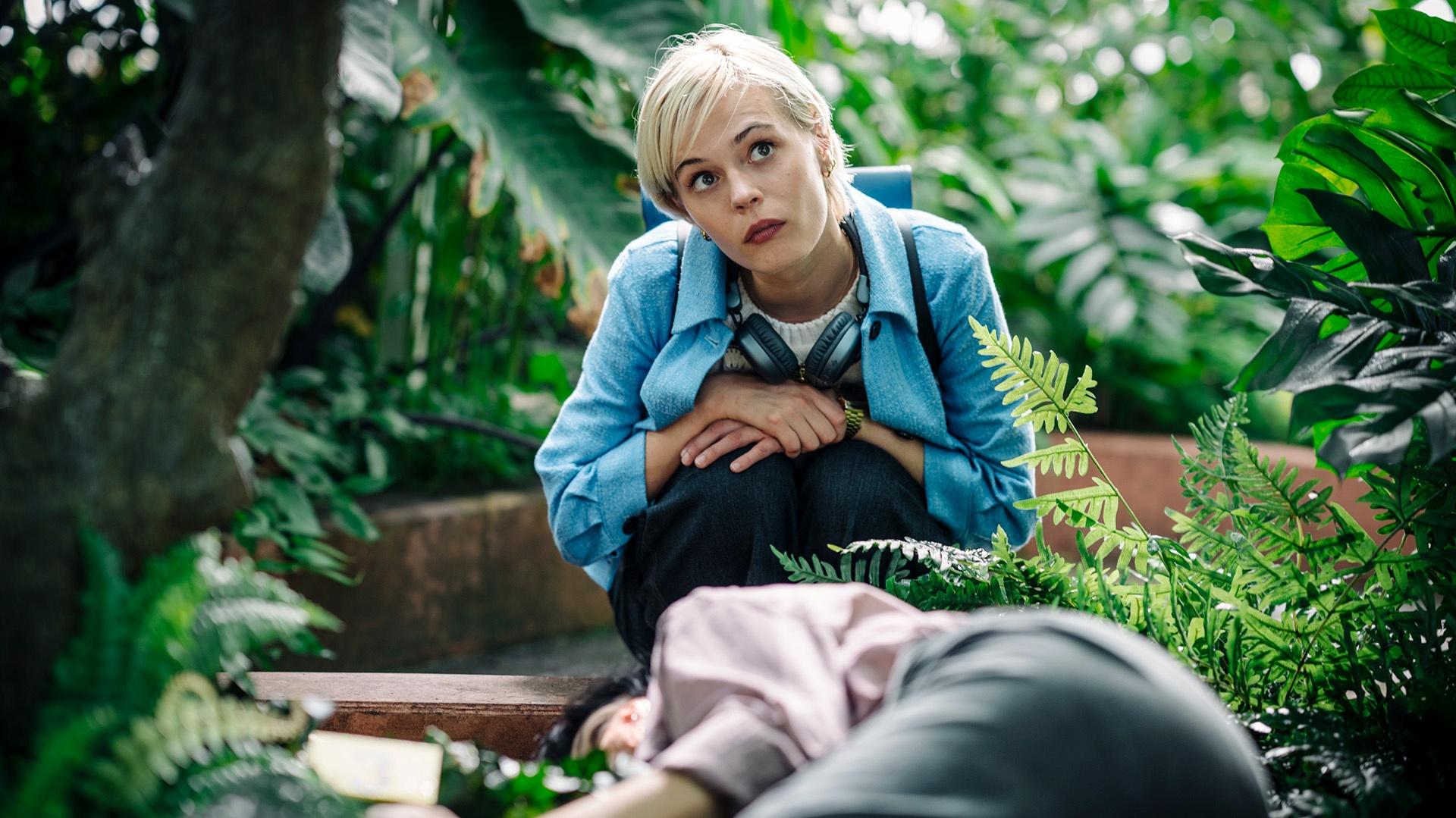 Patience kneeling in a greenhouse