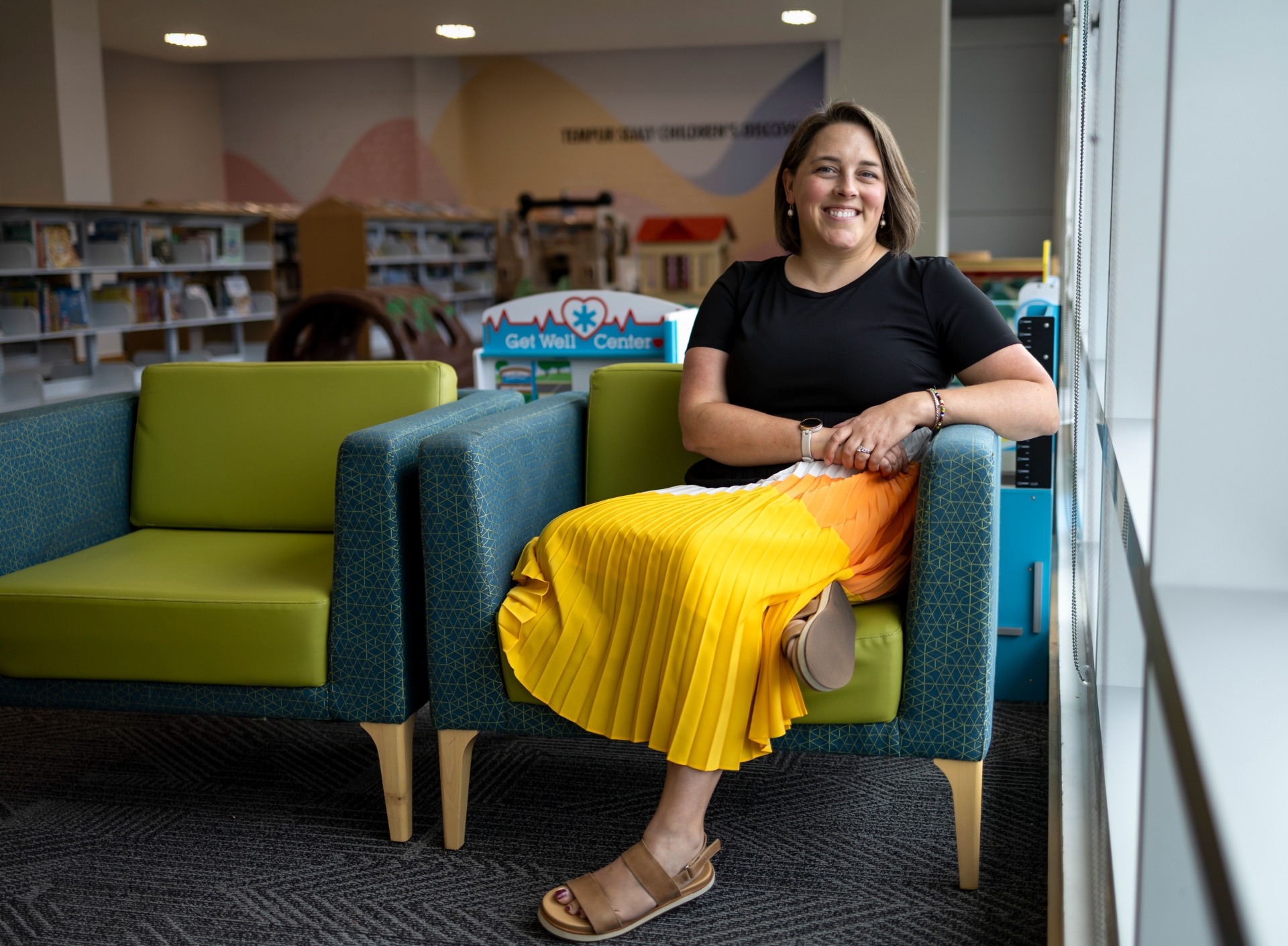 Paige Halpin Smith seated and smiling in a chair in a library.