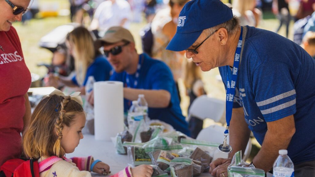 KET employees running an event booth for kids and families. An employee looks at an activity with a small child.