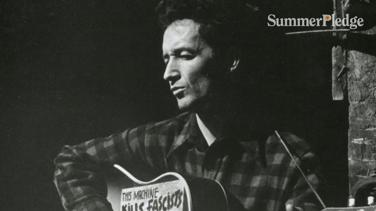 Black and white photo of Woody Guthrie and his guitar