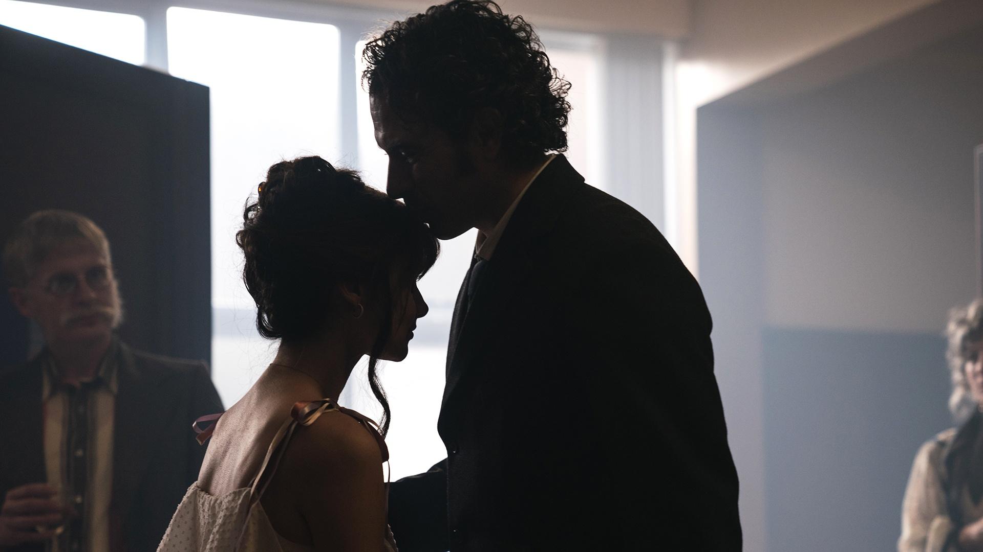Cushla and Michael, mostly in silhouette as he kisses the top of her head