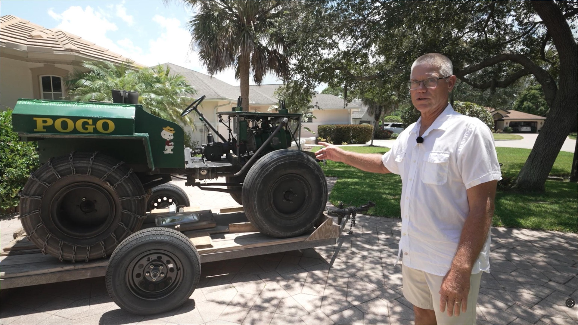 Person gestures to swamp buggy on a trailer in front of a house in Florida