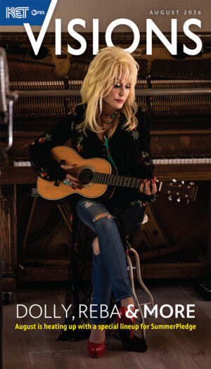 Dolly Parton seated on a piano bench in front of a piano playing a guitar on the cover of August 2026 Visions